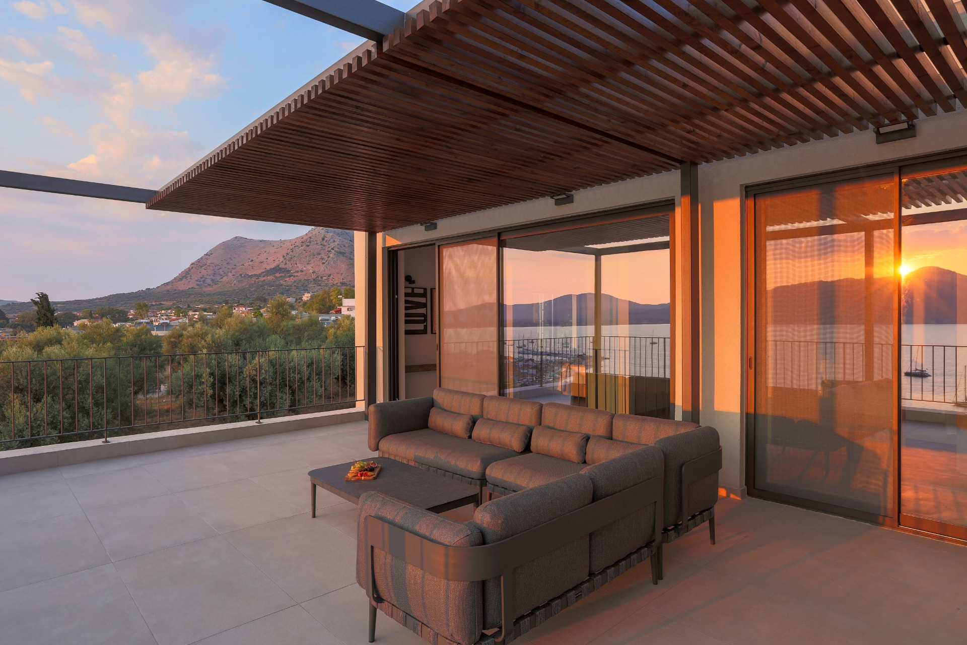 Pergola-covered terrace with corner sofa glowing in golden sunset light