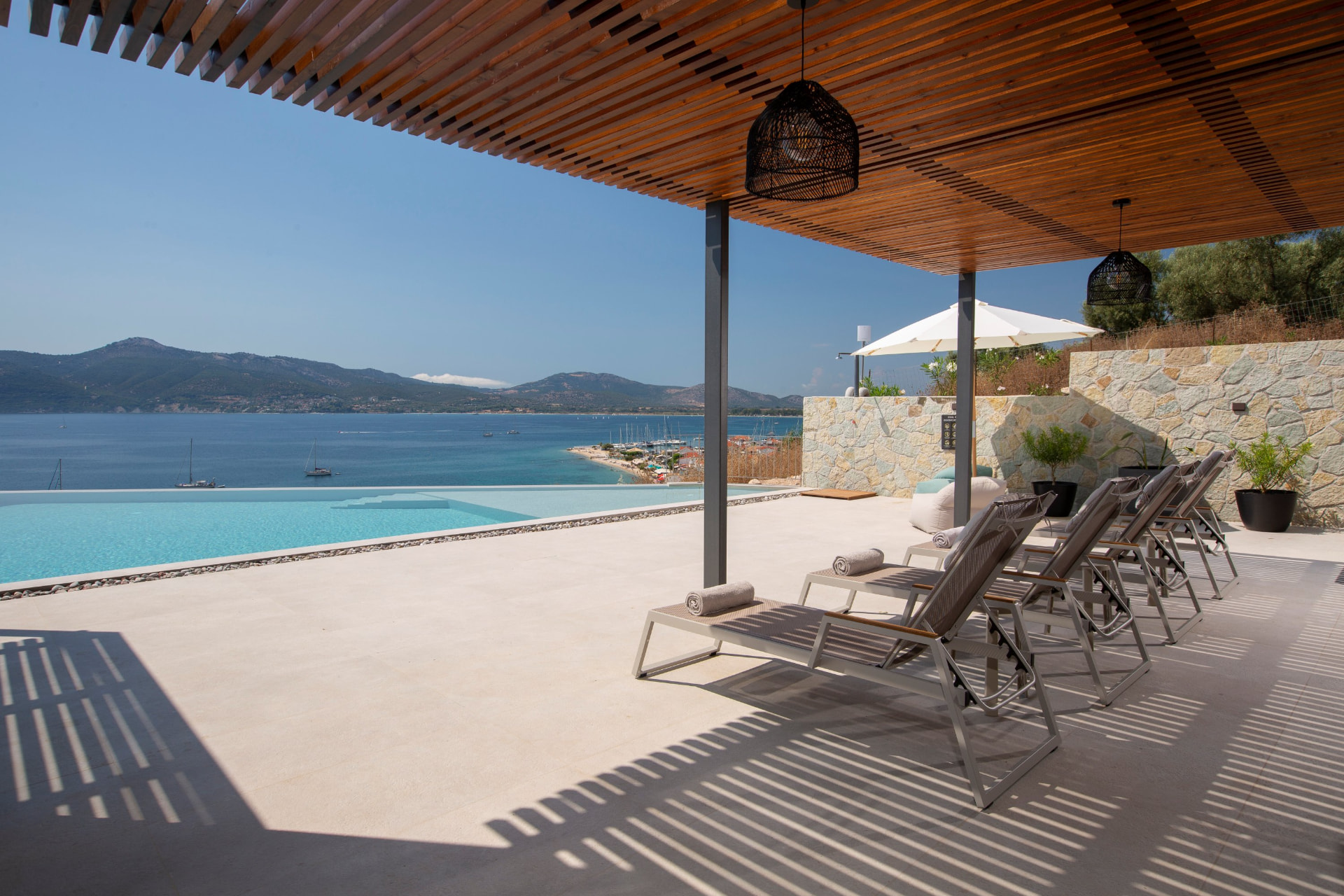 Shaded pergola terrace with sun loungers above Paleros bay