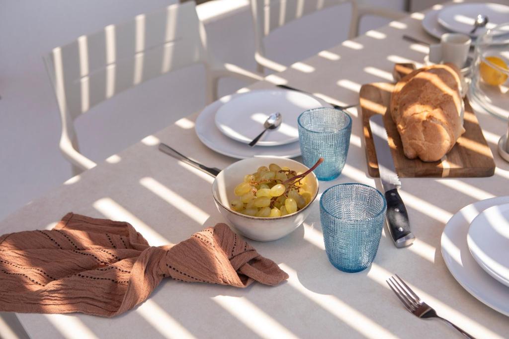 Breakfast table with fresh bread, grapes and blue glassware in striped sunlight