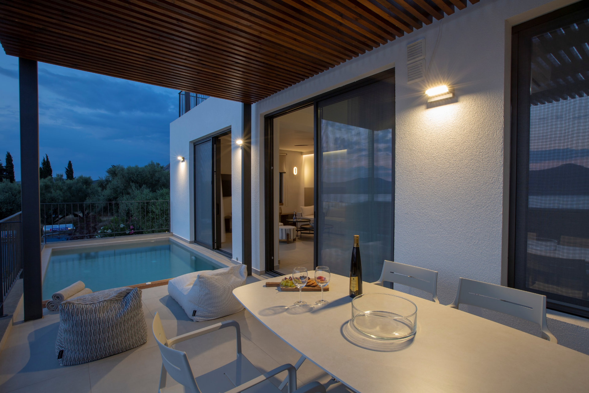 Evening terrace with dining table, bean bags and lit plunge pool