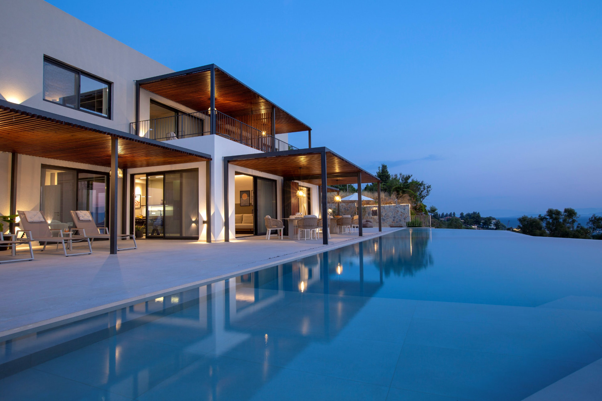 Villa exterior at blue hour with the infinity pool mirroring the lit facade