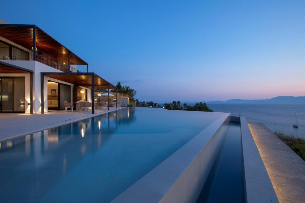 Infinity pool at dusk running alongside the villa with the Ionian Sea beyond