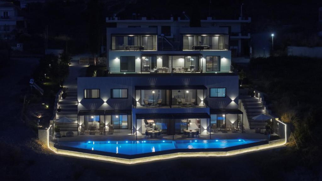 Aerial night view of ZOE Sea View Villas with the illuminated pool