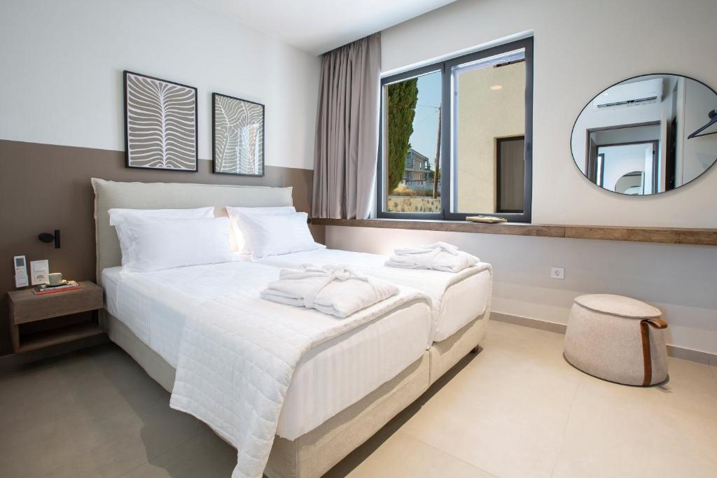 Twin bedroom with white linens, mirror and window seat