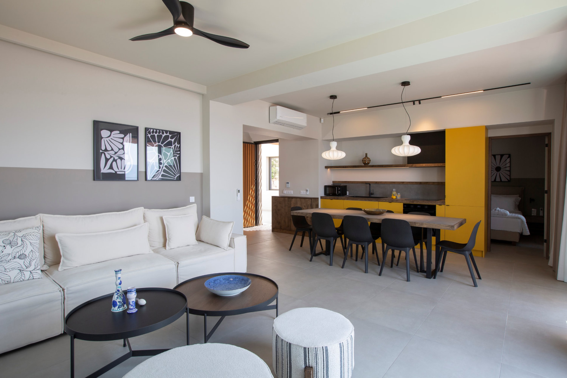 Bright living room with white sofa and yellow kitchen dining space