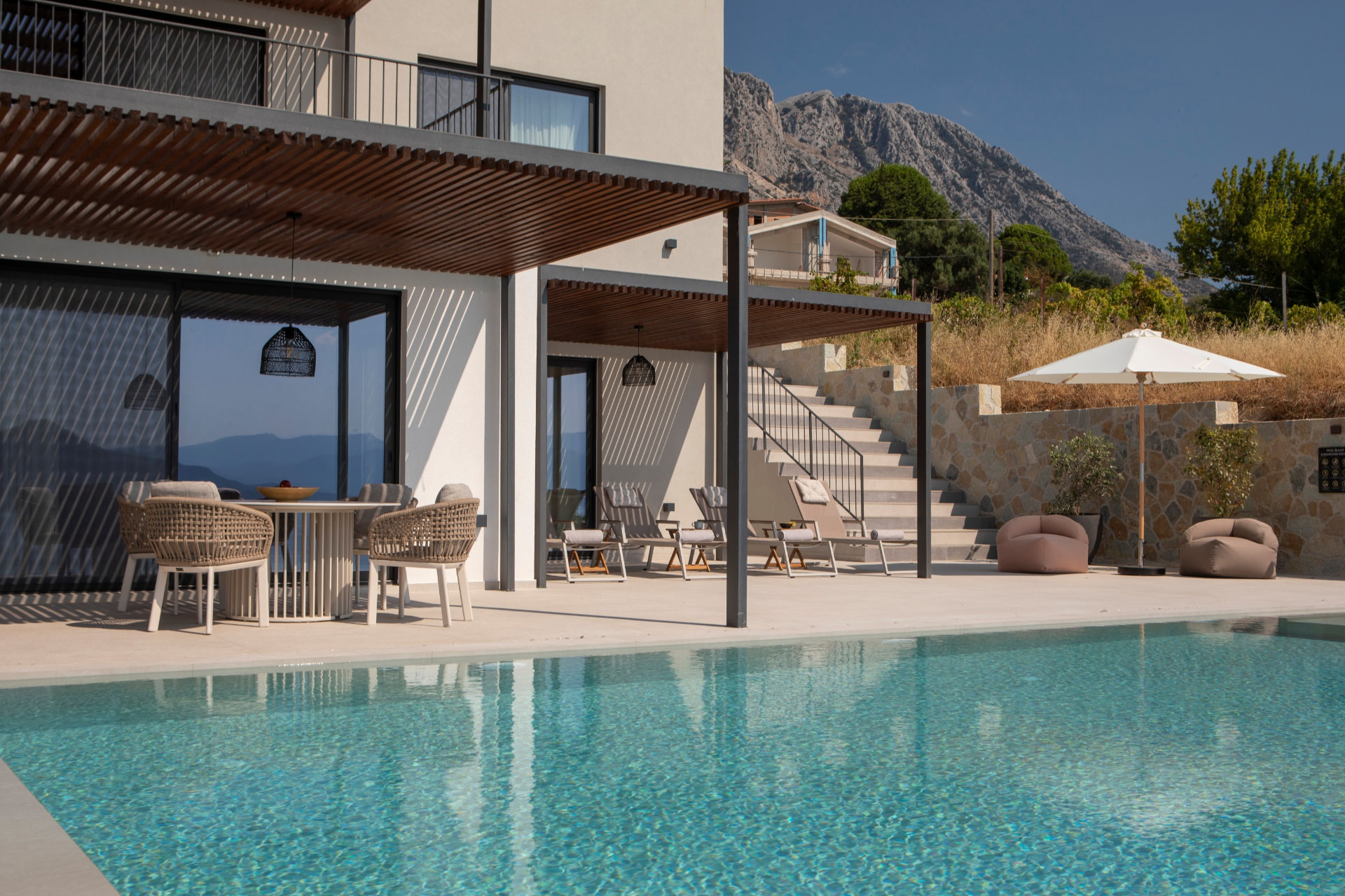 Poolside terrace with dining area, loungers and mountain backdrop