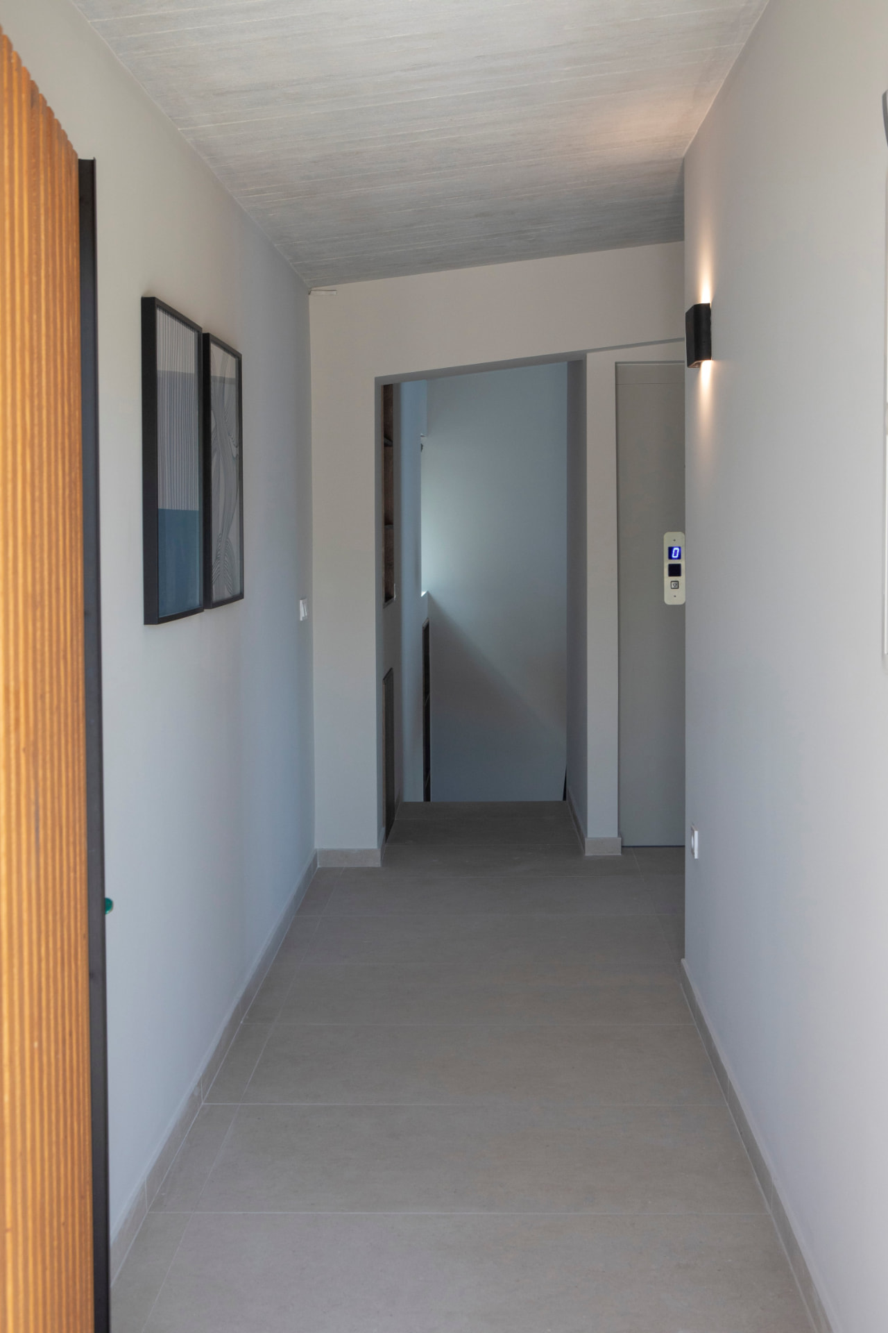 Interior hallway with framed prints, timber screen and soft wall lighting