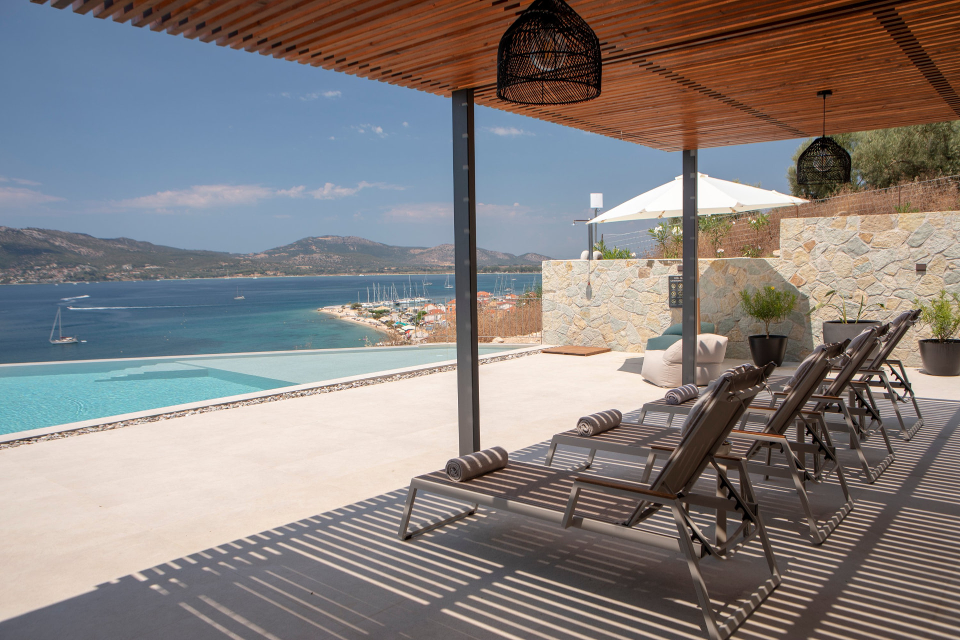 Shaded sun loungers under the pergola beside the infinity pool