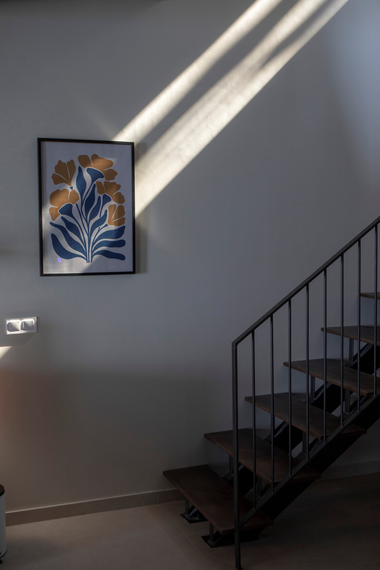 Sunlit stairwell with framed botanical print and timber steps