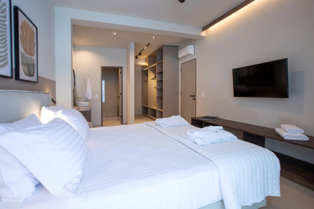 Twin bedroom with white linens, wall-mounted TV and open walk-in wardrobe