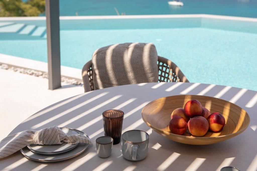 Poolside table with a bowl of peaches and sea views through pergola shadows