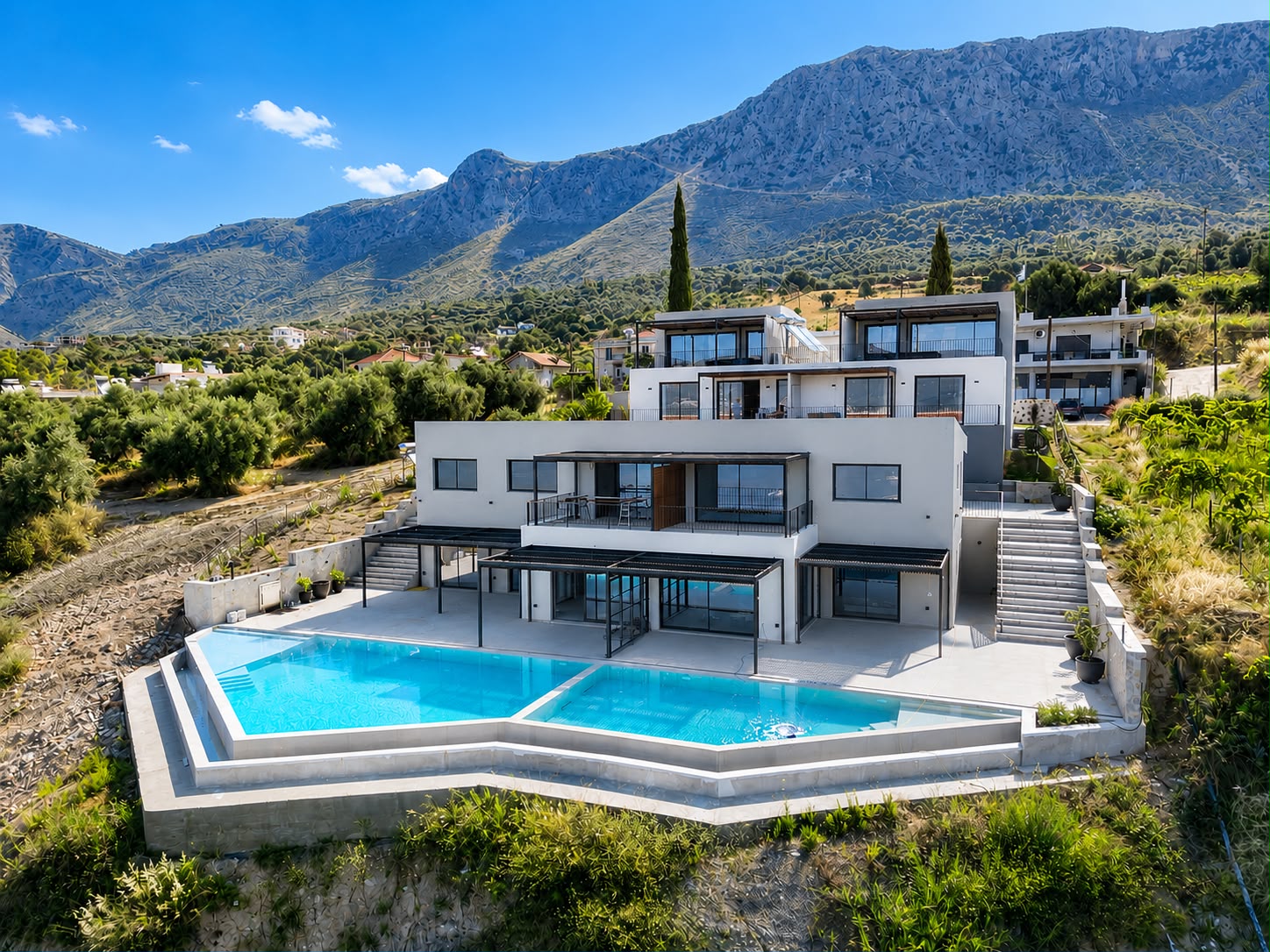 Aerial view of ZOE Sea View Villas with the twin infinity pools and mountain backdrop