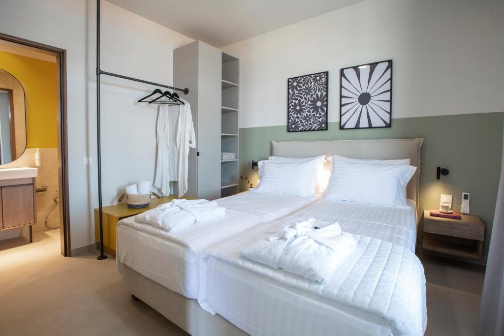 Bedroom with white linens, robes and en-suite bathroom in soft sage tones
