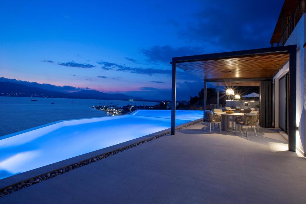 Infinity pool glowing at dusk above the lights of Paleros harbour