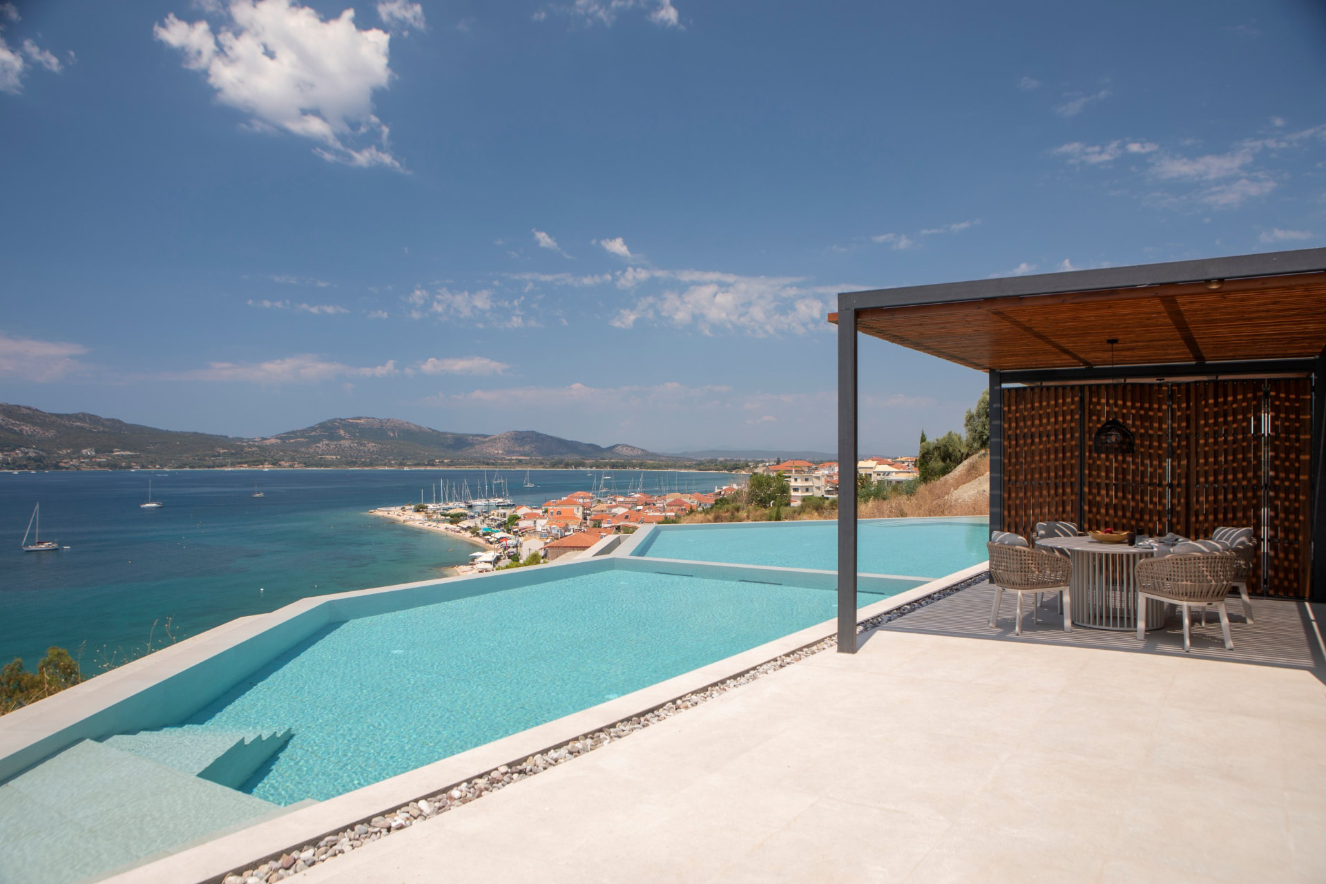 Twin infinity pools and shaded dining terrace above Paleros bay
